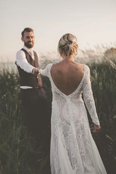 a bride and groom walking through tall grass