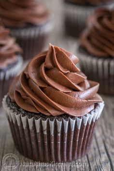 cupcakes with chocolate frosting sitting on a wooden table