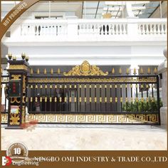 an ornate iron gate with gold trimmings in front of a white and black building