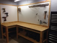 a workbench with lots of tools hanging on the wall