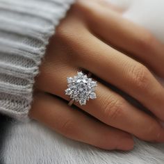 a woman's hand with a diamond ring on top of her finger and white fur