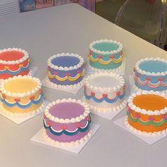 six cakes are arranged on top of each other in different colors and designs, with white frosting around the edges