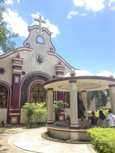 people sitting on the porch of a small church with a cross at the top and an arched doorway