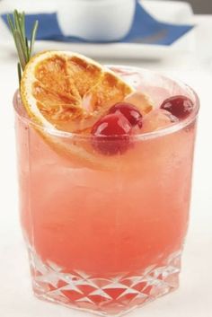 a drink with orange slices and cherries on the rim, garnished with rosemary