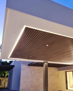 an outdoor covered patio area with lights on the ceiling and concrete flooring, along side a white building