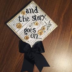 a graduation cap that says and the story goes on with flowers in black ribbon around it