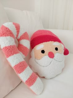 a santa clause stuffed animal sitting on top of a white couch next to a candy cane