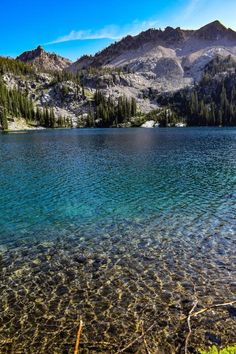 a mountain lake with clear water surrounded by trees