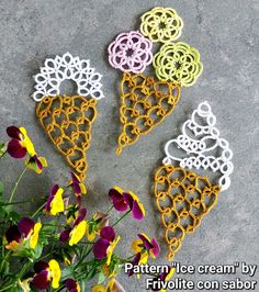 four crochet ice cream cones sitting on top of a cement floor next to flowers