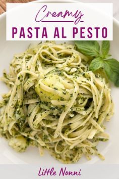 a white plate topped with pasta covered in pesto