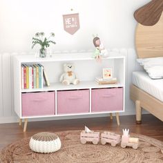 a child's bedroom with pink and white storage bins on the floor next to a bed