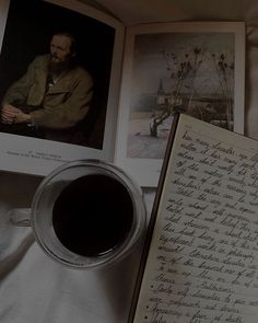 an open book with writing on it next to a cup of coffee and two photos