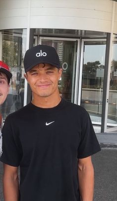 two men standing next to each other in front of a building