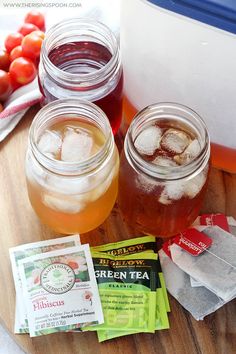 three mason jars filled with liquid and ice sitting on top of a wooden cutting board