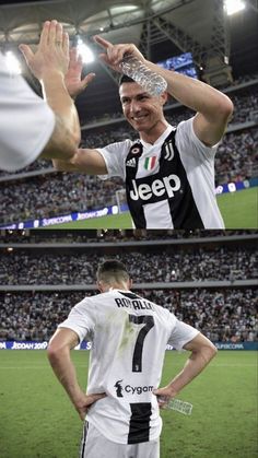 there are two men standing in front of the crowd at a soccer game, one holding his hands up