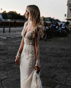 a woman is walking down the street wearing a dress with sheer sleeves and an open back