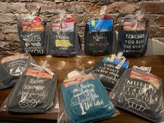 several bags with chalk writing on them sitting on a table next to a brick wall