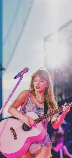 a woman with a pink guitar on stage