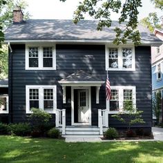 a gray house with an american flag on the front door and window trimmings