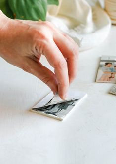 a person's hand reaching for some photos on a table