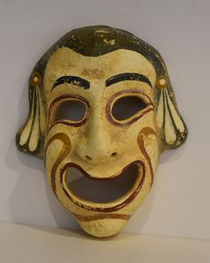 an old mask with a smile on it's face is hanging on the wall