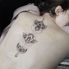 a woman with a tattoo on her back is laying down and looking at the camera