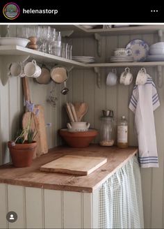 a wooden cutting board sitting on top of a counter next to pots and pans