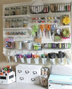 organized craft room with pegboard, scissors and other items on the wall behind it