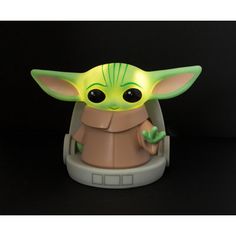 a star wars yoda toy sitting on top of a black table next to a green light