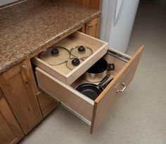 an open drawer with pots and pans in it