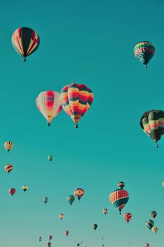 many hot air balloons flying in the sky