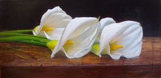 three white flowers sitting on top of a wooden table