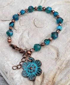 a bracelet with a blue flower charm on it's end and a copper clasp