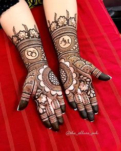 two hands with henna tattoos on them sitting on top of a red table cloth