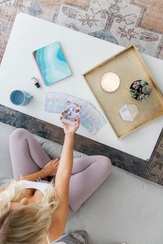 a woman is sitting on the couch looking at her cell phone and holding a map