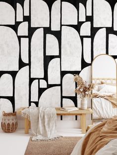 a bedroom with black and white wallpaper that has geometric shapes on it, along with a bed