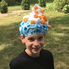 a young boy wearing a blue and white hat with oranges on it's head