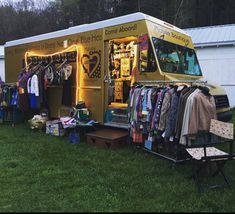 a yellow food truck parked in the grass with clothes on it's rack and other items