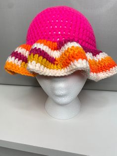 a white mannequin head wearing a multicolored knitted clochet hat