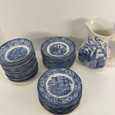 a stack of blue and white plates next to a pitcher