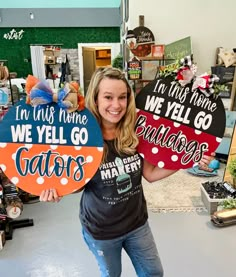 a woman holding two signs that say i'm this home, we'll go bulldogs