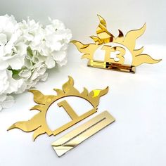 two gold and silver metal business cards next to white hydranges on a table