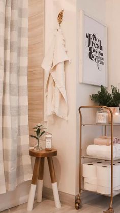 a bathroom with white towels and wooden stools next to a shower curtain on the wall