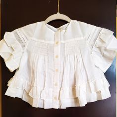 Brand New With Tags. Beautiful White Cotton Girl's Blouse With A Round Neckline, Ruched Panel On The Chest, Loose Pleats And An Embossed Button Closure In The Front. There Are Frilly Trims On The Shoulder And Hemline. Color: White Hue Branded Burberry Tab Above The Hemline. Fully Lined. 100% Cotton. Frilly Blouse, Burberry Shirts, Girls Blouse, White Cotton, Kids Shirts, Round Neckline, Shirts Tops, Burberry, Color White