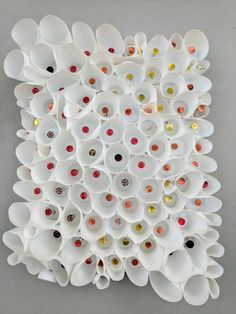 an art piece made out of cups and spoons on a gray surface with white walls