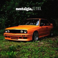 an orange car is parked in the grass near some trees and bushes, with the words nostalgica ultra above it