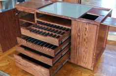 a wooden cabinet with drawers and glass top on the floor in a room that has hardwood floors