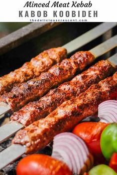 meat skewers are being cooked on the grill with tomatoes, onions and peppers