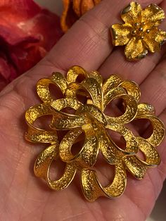 "I matched a rich gold plate dimensional ribbons brooch and a pair of flower clip earrings and I think I love it. They aren't identical - they might be better than that. No names which is also strange. The brooch is a large domed swirl of narrow textured ribbons. 2\" diameter. Earrings are sweet dimensional flowers with clip backs. Each little petal has a turned up edge. So cute. 1\" diameter. Clasp on pin is secure. Clip backs on earrings are secure. Perfect condition." Vintage Gold Flower Clip-on Earrings, Gold Flower Brooch For Formal Occasions, Gold Flower Brooch For Party, Gold Flower Brooches For Party, Gold Flower Shaped Brooch For Gift, Gold Flower-shaped Brooch For Gift, Gold Flower Shaped Brooch As Gift, Gold Flower-shaped Brooches For Gifts, Gold Clip-on Brooch For Wedding