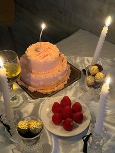 a birthday cake with candles and strawberries on a table